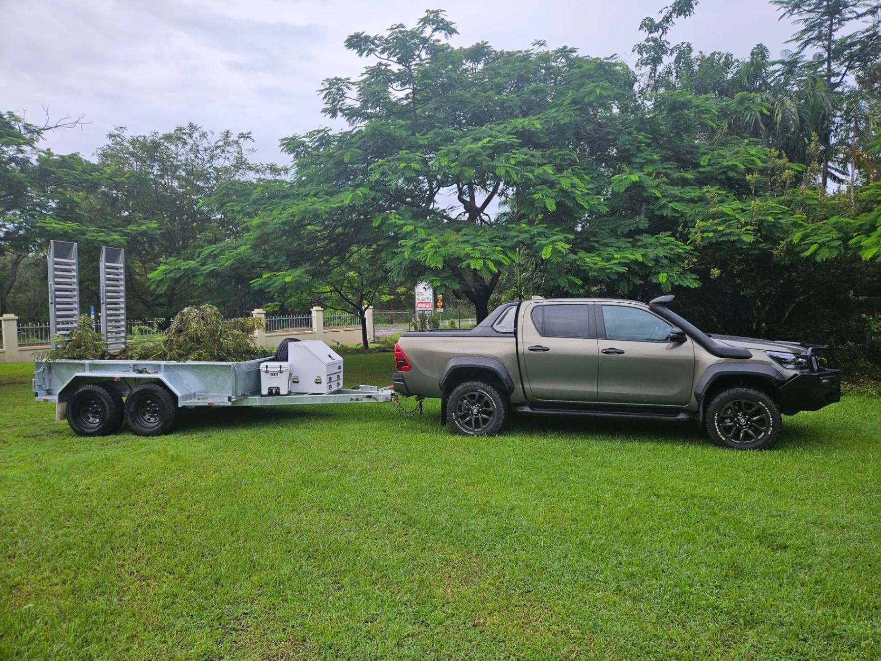 Work ute and trailer loaded with green waste on a mowed lawn