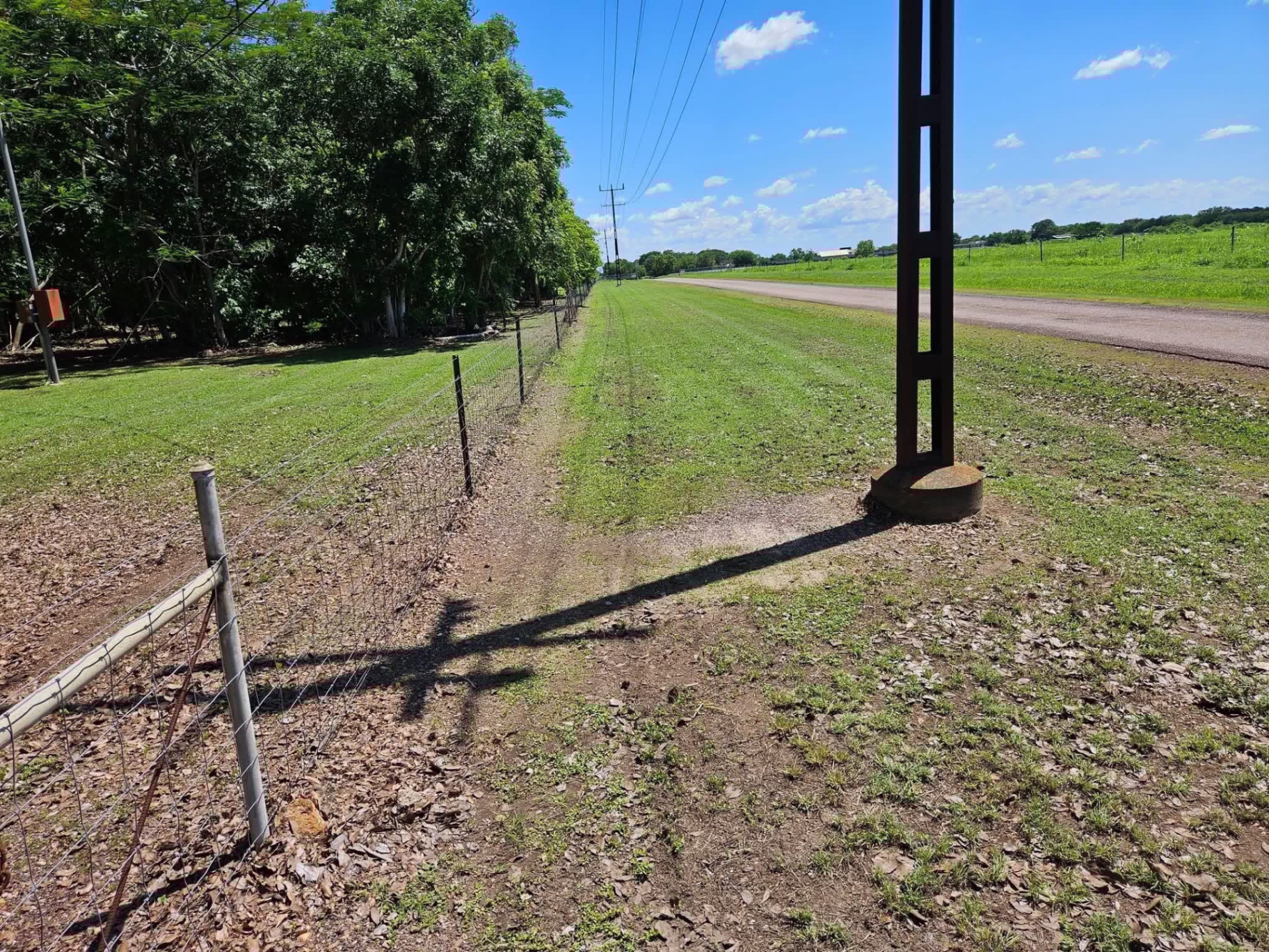 Cleared firebreak along a fence line beside a rural road