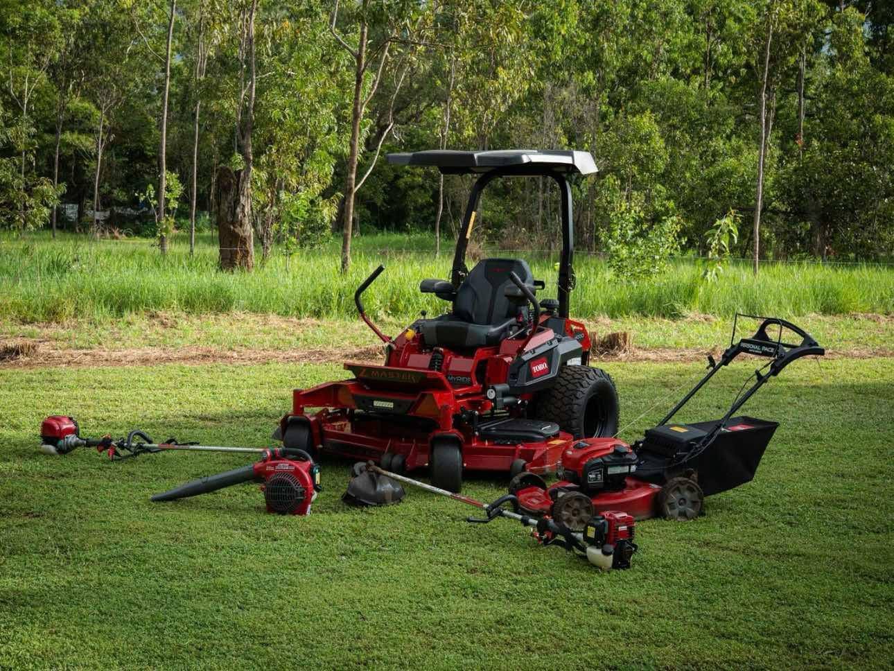 Ride-on mower, push mower, blower and line trimmers on a lawn